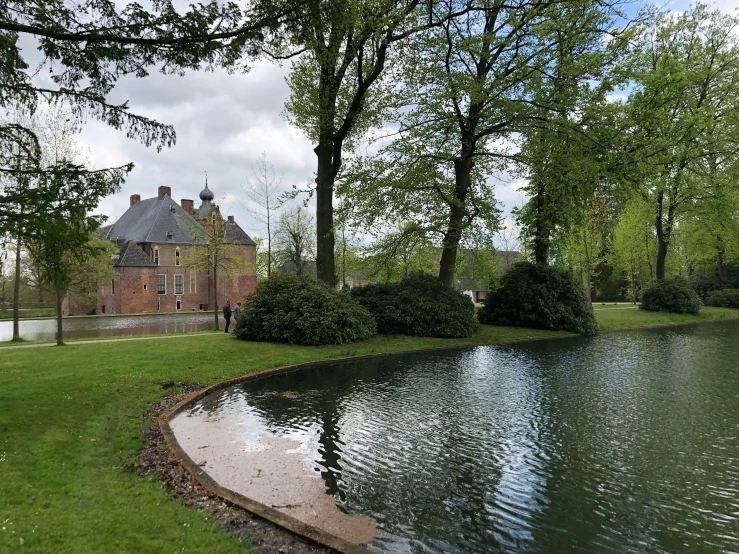 an empty pond near some trees and a large brick building