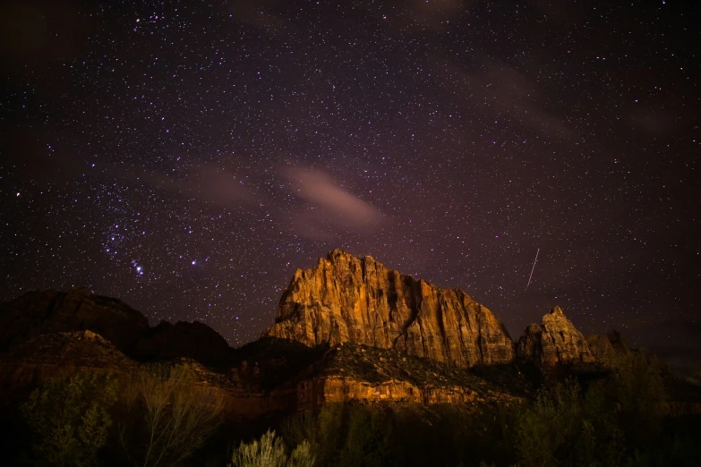 there is a very tall rock formation under a night sky