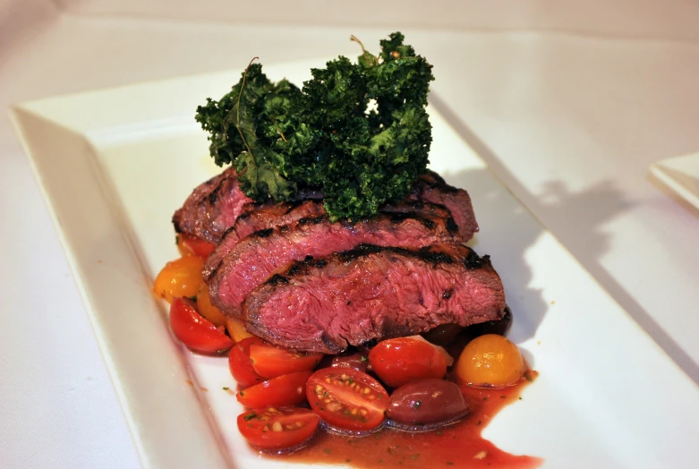 a dinner plate with steak and tomatoes