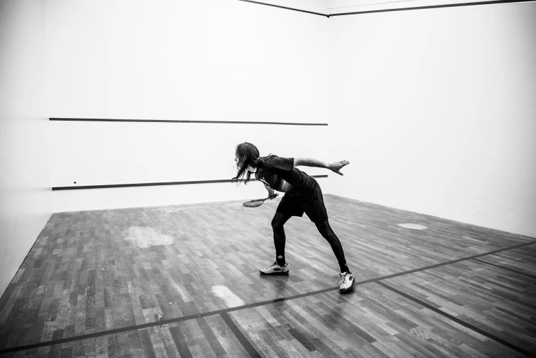 a woman is doing a handstand while holding a tennis racket