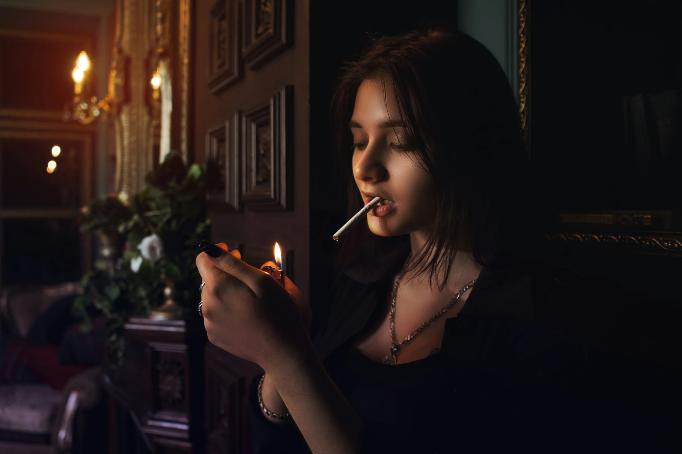 a woman holding a lit cigarette, looking out of a window