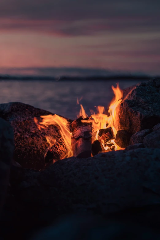 the fire is burning on the rocks near the ocean