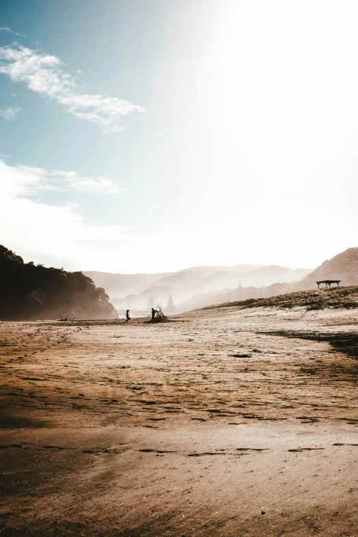 some people are standing in a large area with hills in the background