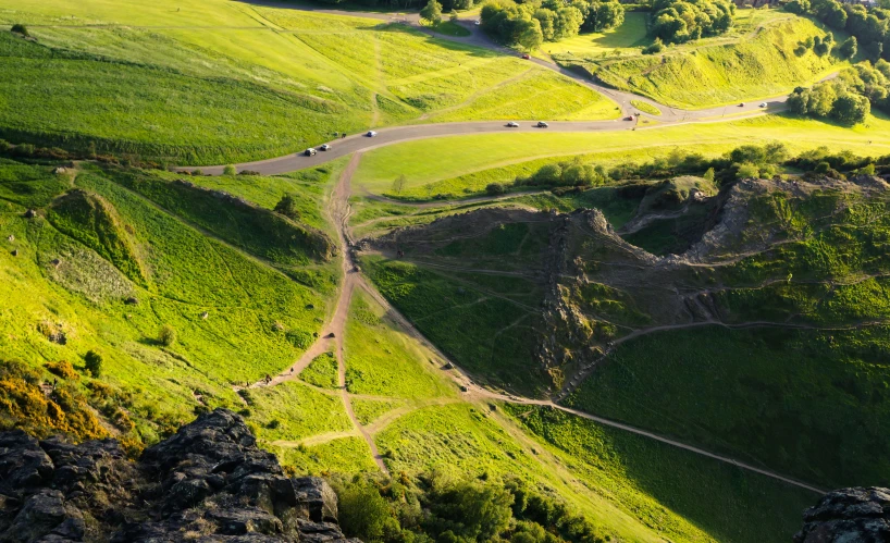 a long dirt road going through a lush green valley