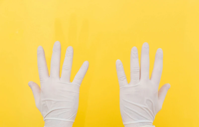 an image of two hands in white gloves on yellow background