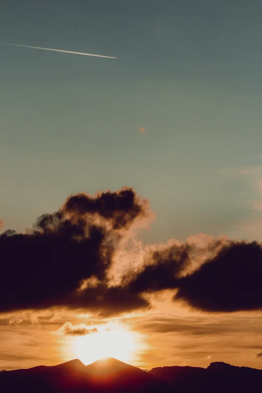 a jet flying above the sunset and mountains