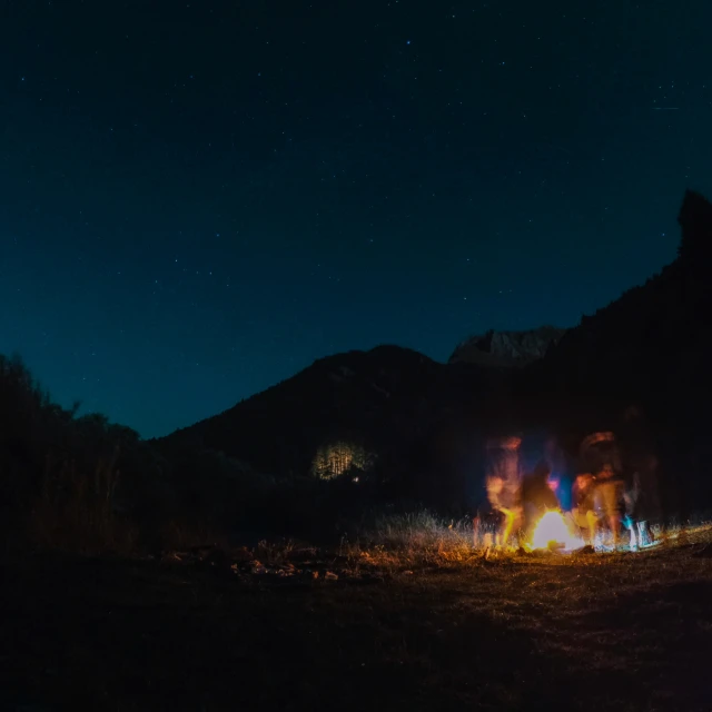 a group of people sitting around a fire while looking at it