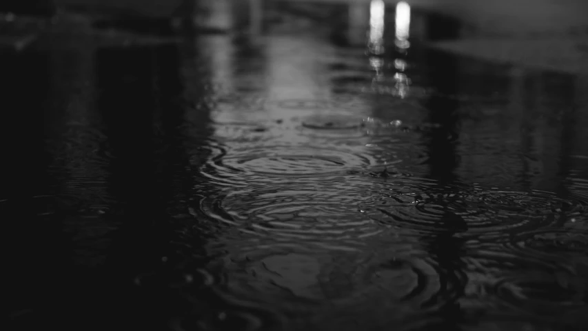 black and white pograph of rain drops falling onto a table top