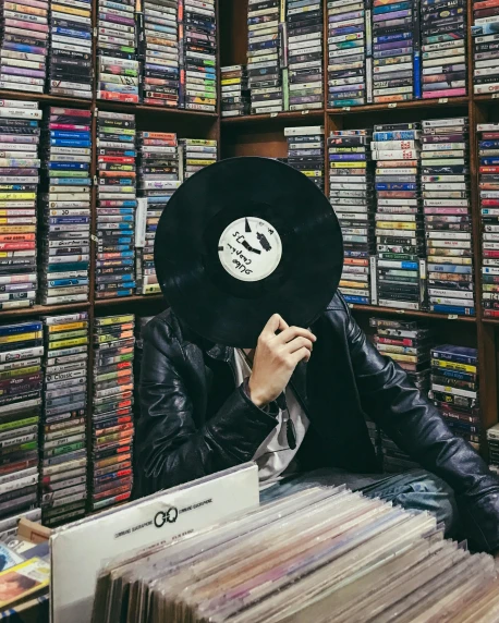 the person is hiding his face behind a record