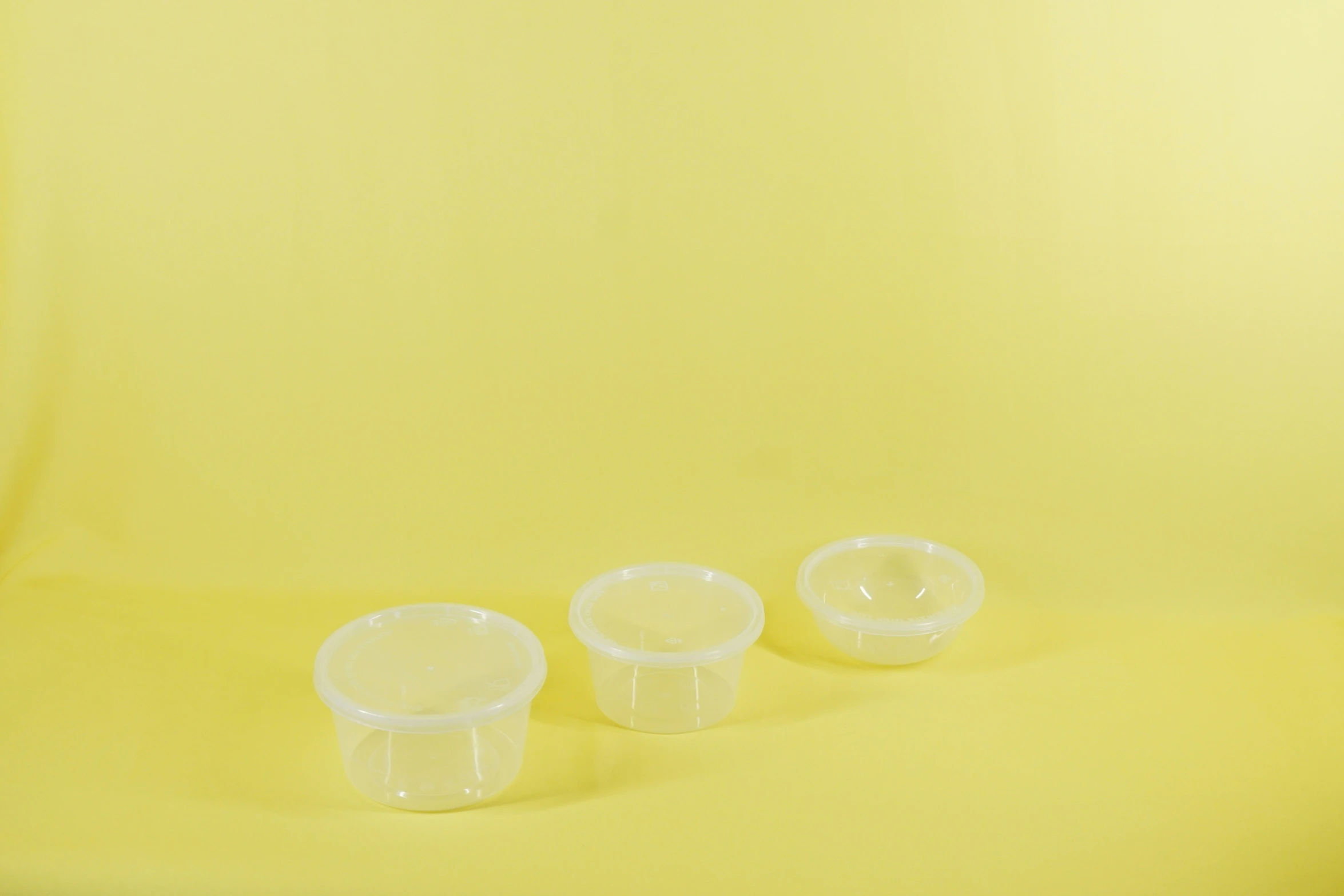 three clear plastic containers sitting on top of yellow background