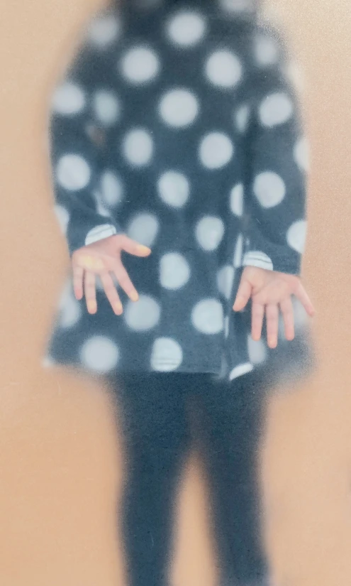 a close up view of a child's hands, blurred, with polka dot pattern