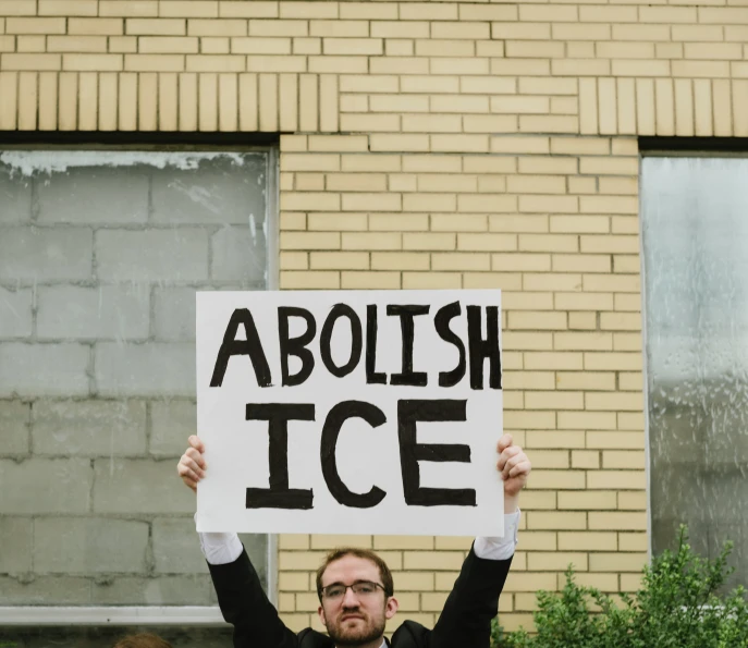 a man holding a sign that reads abolish ice