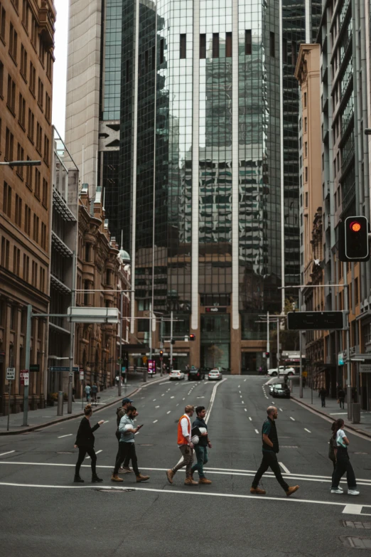 pedestrians crossing the street in between large buildings