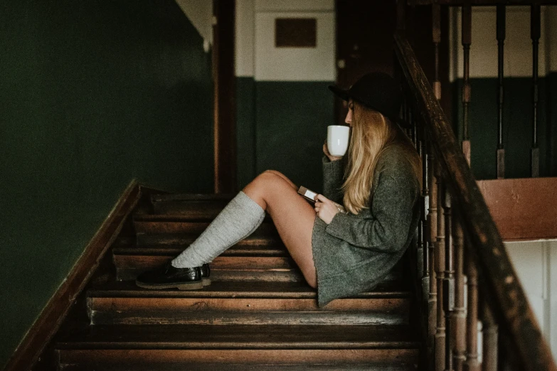 a woman wearing boots, sitting on a stair case