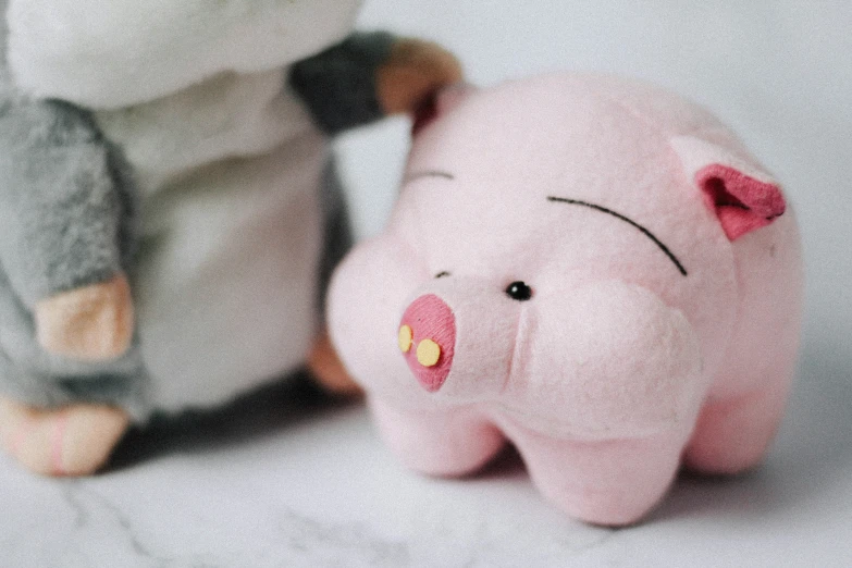 a small pink pig sitting next to a stuffed monkey