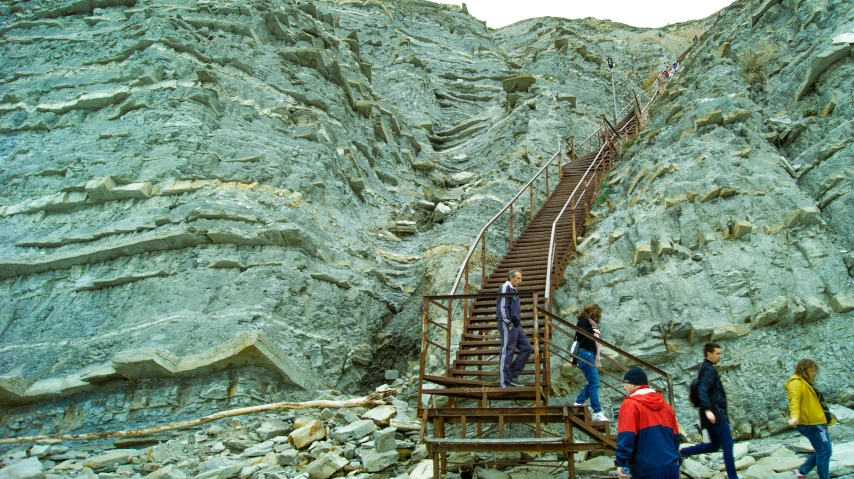 four people stand near some rocks as one holds onto a stair rail