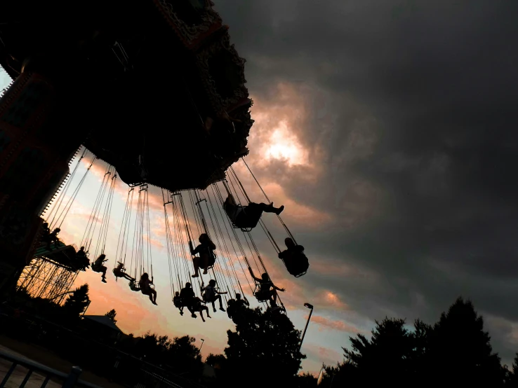 a group of people riding on swings in a park at night