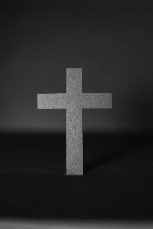 a white cross is standing alone in the dark