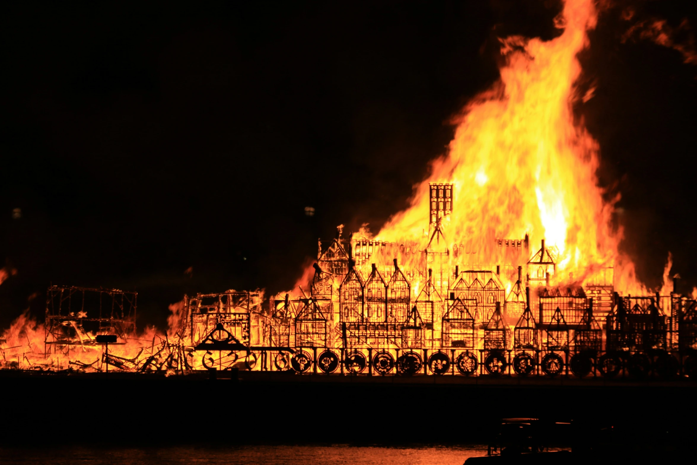 an oil refinery in flames at night with its lit up
