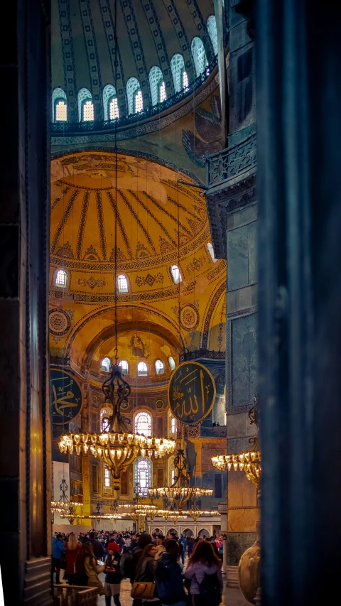 a po taken through a glass window looking at a huge church with a chandelier and lights on it