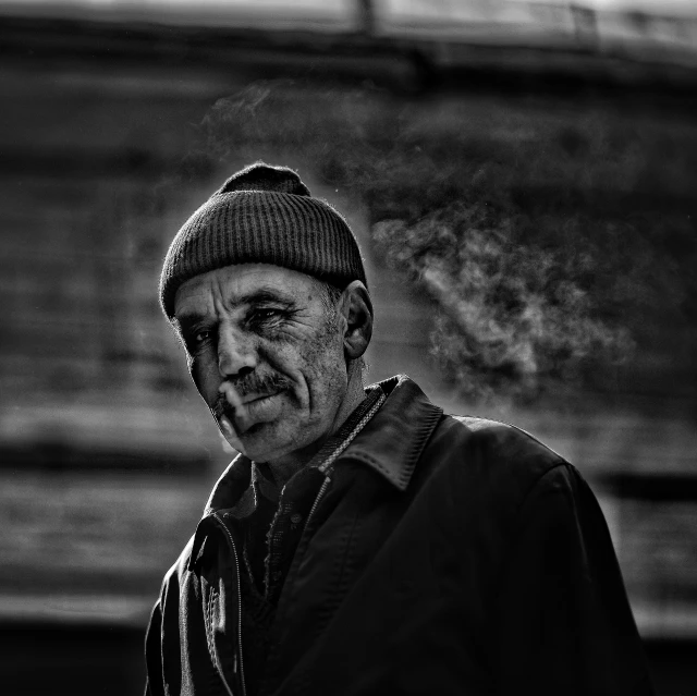 a man in a beanie wearing a hat smoking