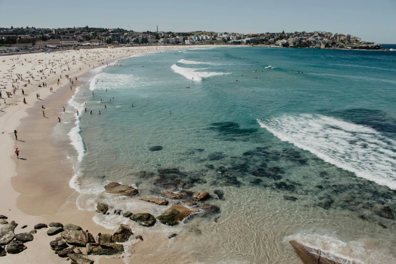 people are in the water near some sand and rocks