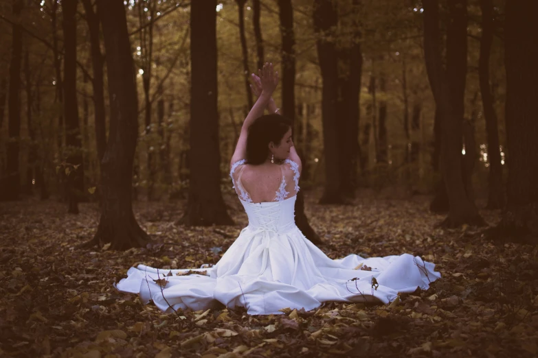 a woman sits in the woods on her wedding day