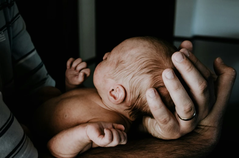 a baby's head is held close to its mother's chest