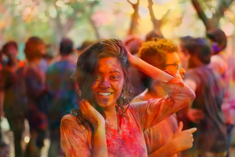 a woman covered in colored dye smiles at the camera