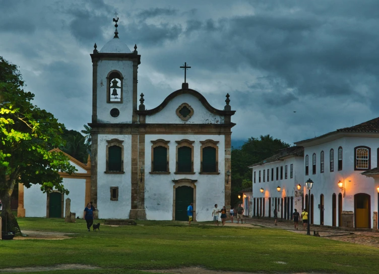 a church with a clock tower next to two white buildings