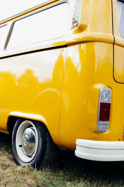 a yellow bus parked in a field near another truck