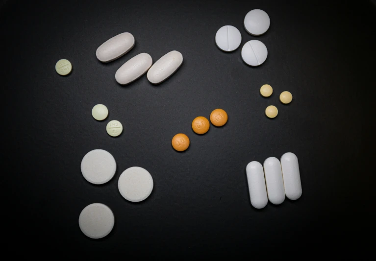 a black table with multiple pills and vitamin capsules