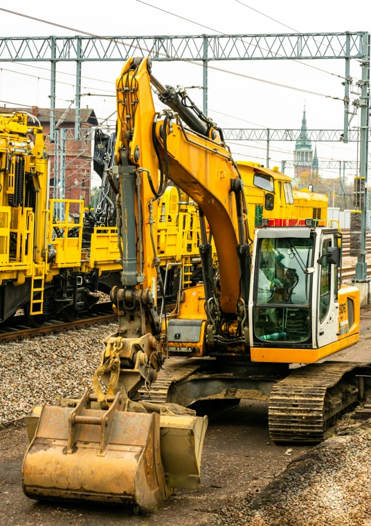 a yellow excavator is shown on the railroad tracks