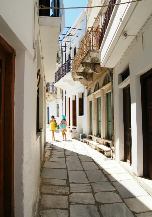 a couple walks down a stone street with their umbrella