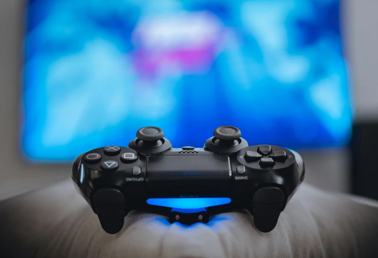 a black game controller in front of a tv