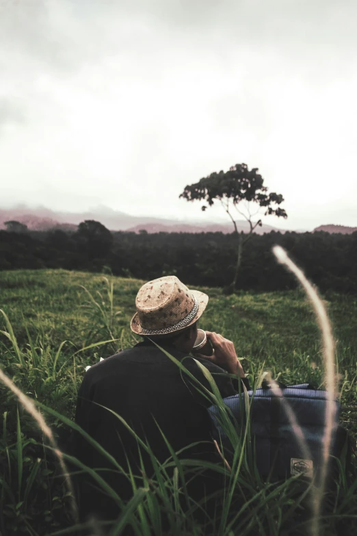 the person in the hat is sitting on the grass