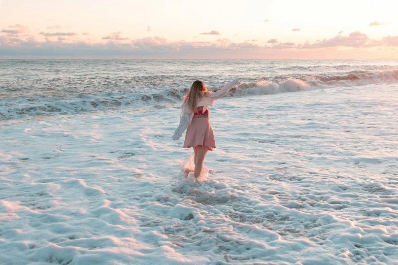 a woman walking across a sandy beach next to the ocean