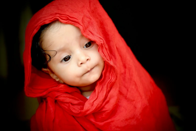 a little girl smiling and hiding under a blanket