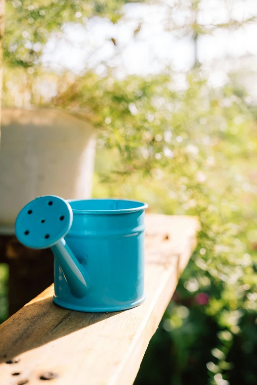 the turquoise cup on top of the wooden table looks like it has a lid that holds a plastic spatula