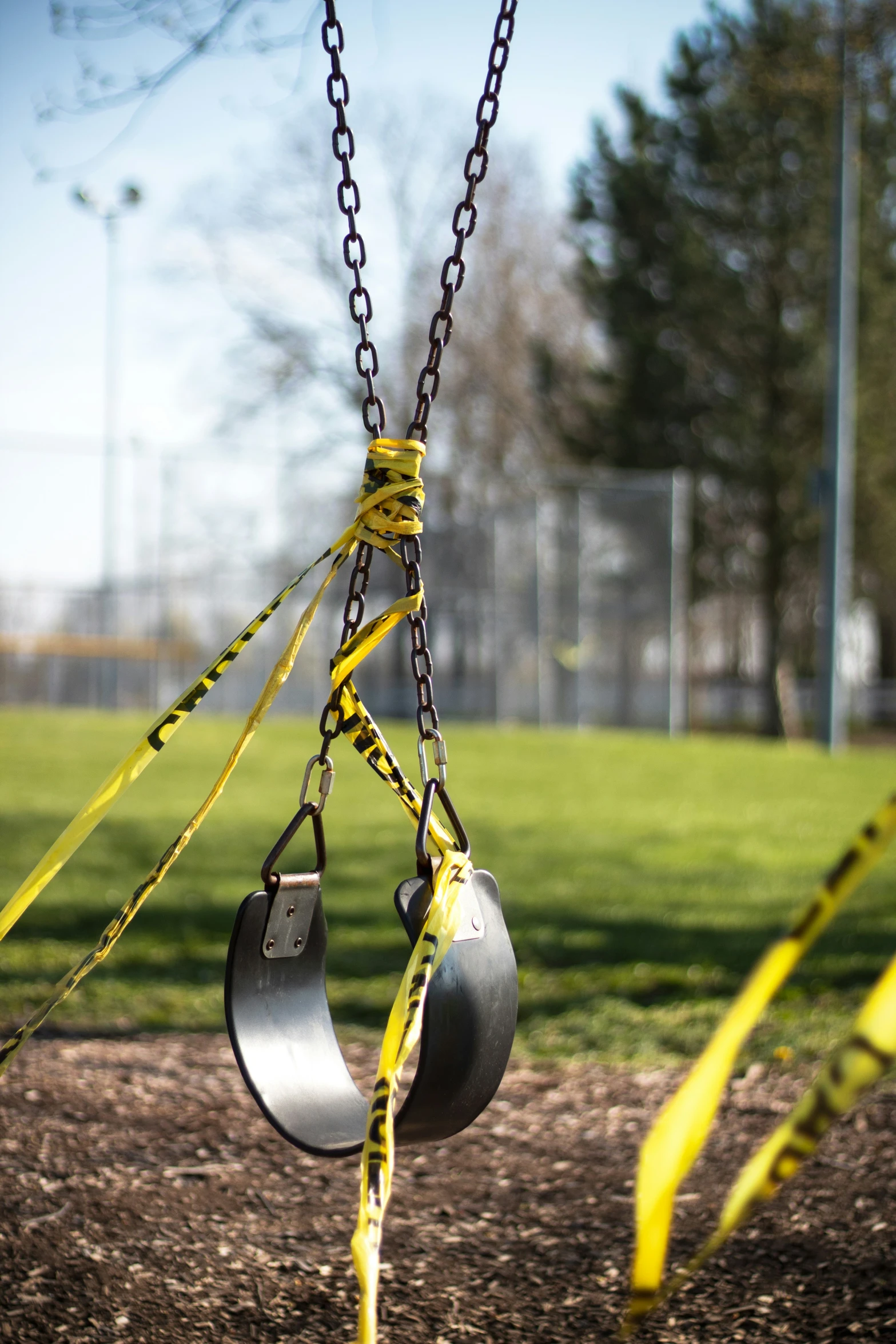 two metal pots hang from chains next to a green park