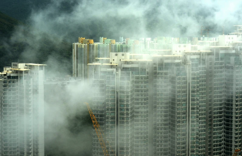 a group of tall buildings with fog coming off the tops