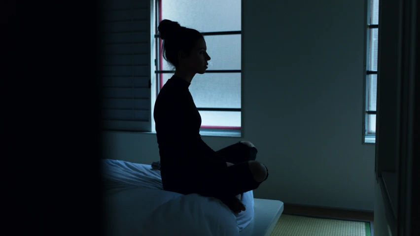 woman sitting on bed in dimly lit room