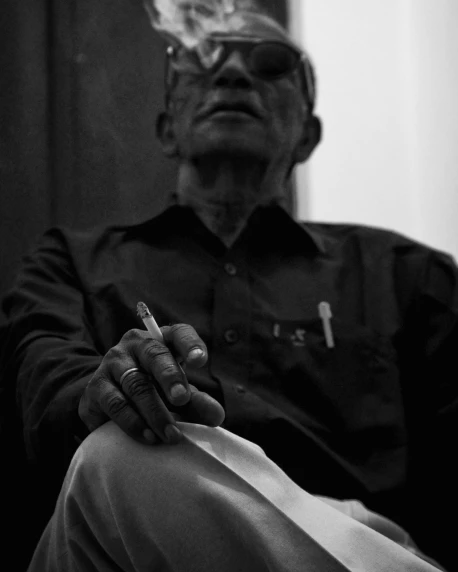 a man smoking a cigarette in his lap with a red shirt on