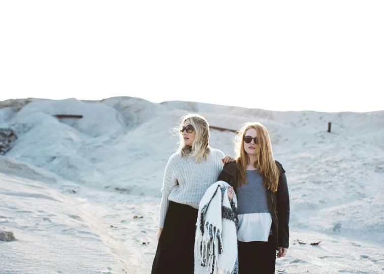 two women standing on the beach wearing polar bear scarves