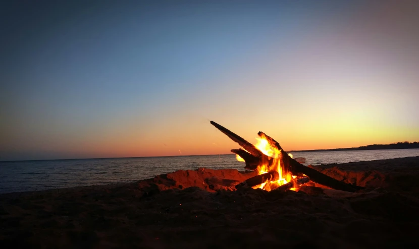 the fire is burning on a beach by the water