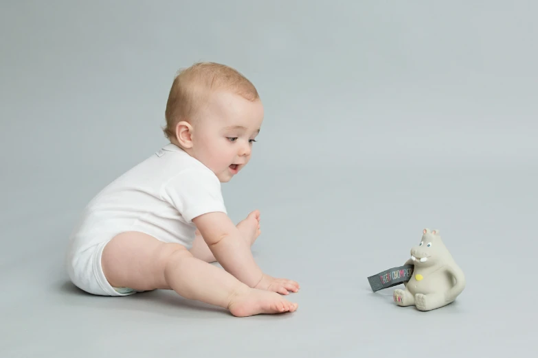 a baby playing with an electronic toy cat