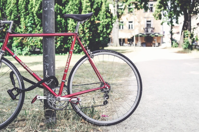 a red bicycle leaning on a pole in the grass