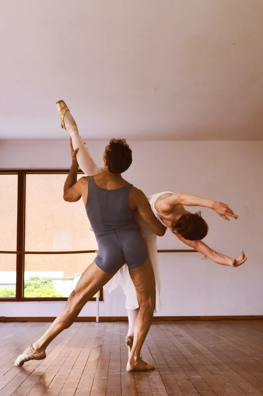 two people in tights dance on a hard wood floor