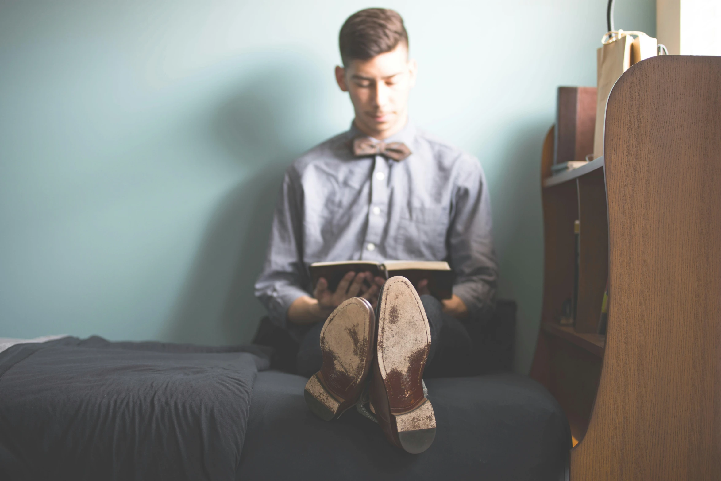 a boy sitting on his bed reading a book