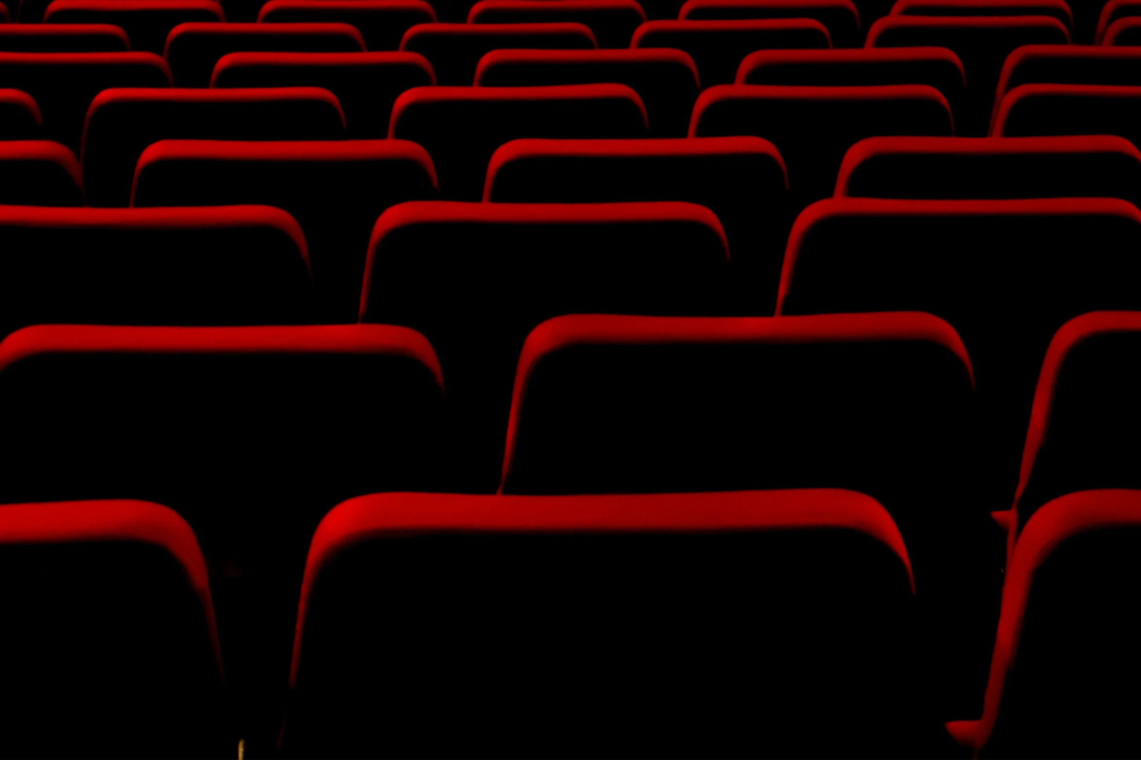 an empty red theater auditorium with rows of seats